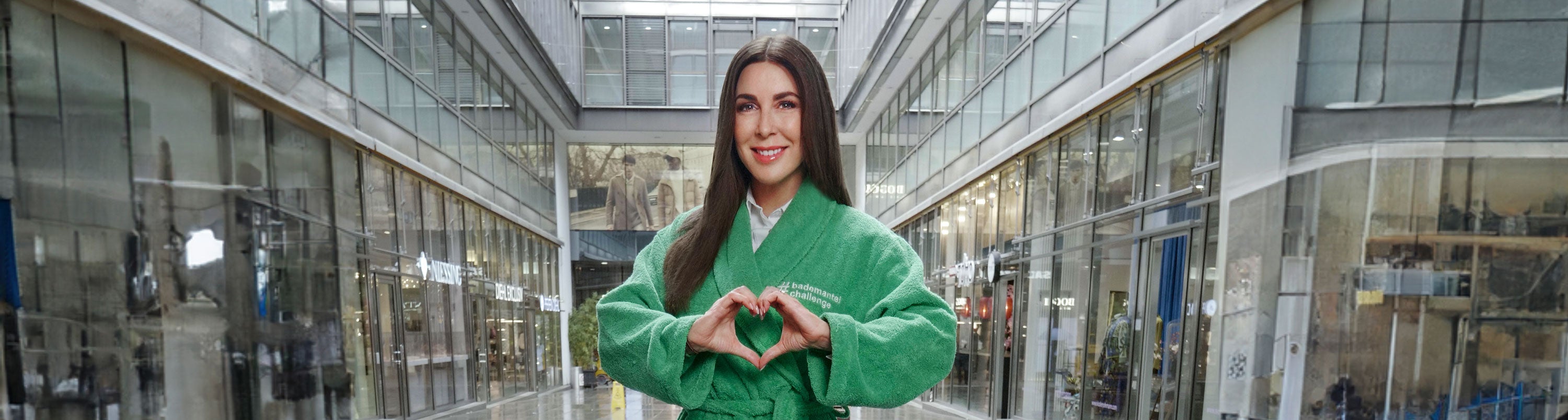 Judith Williams steht für die Kampagne der DZNE in einem grünen Bademittel mitten in einer Einkaufsstraße