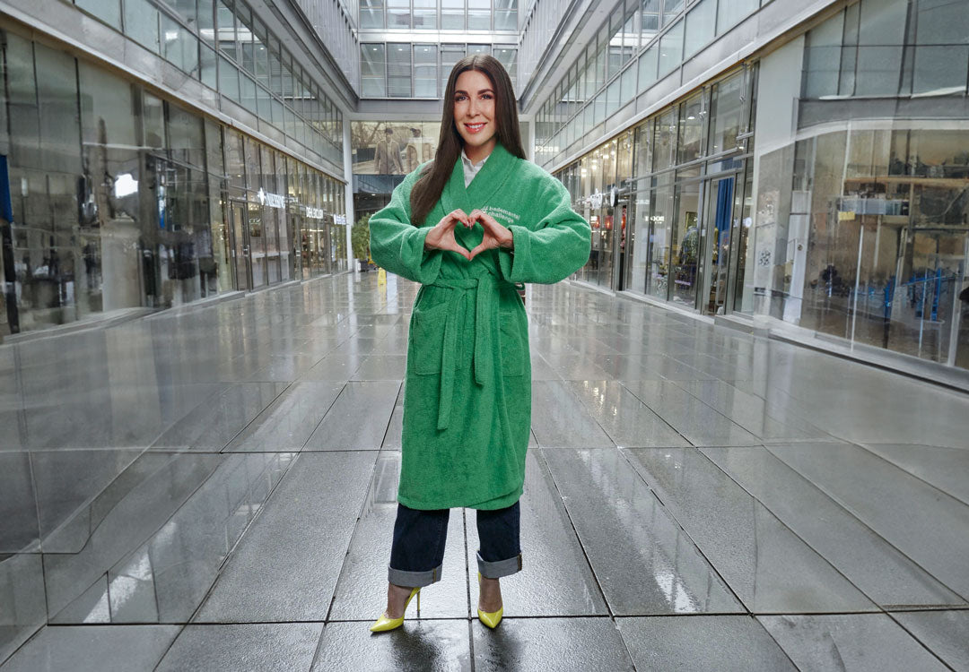 Judith Williams steht für die Kampagne der DZNE in einem grünen Bademittel mitten in einer Einkaufsstraße