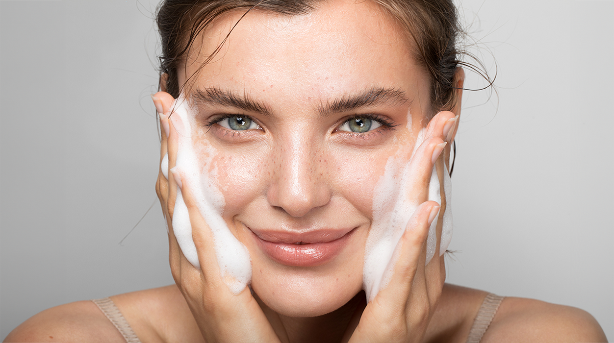 Model trägt Reinigungsschaum auf ihr Gesicht auf.