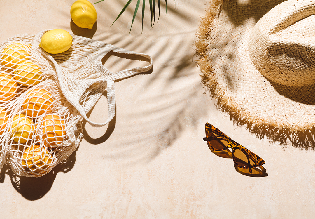 Urlaubsbild mit Sonnenbrille, Sonnenhut und Zitronen.