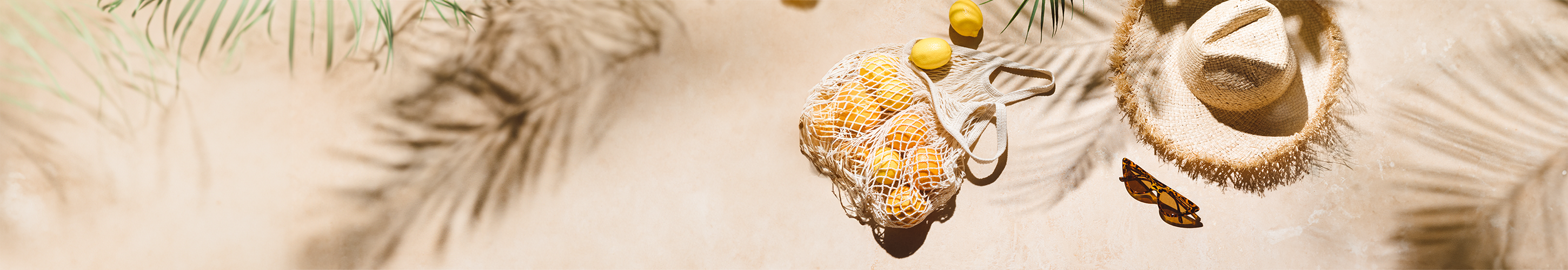 Urlaubsbild, mit Sonnenbrille, Sonnenhut und Zitronen.