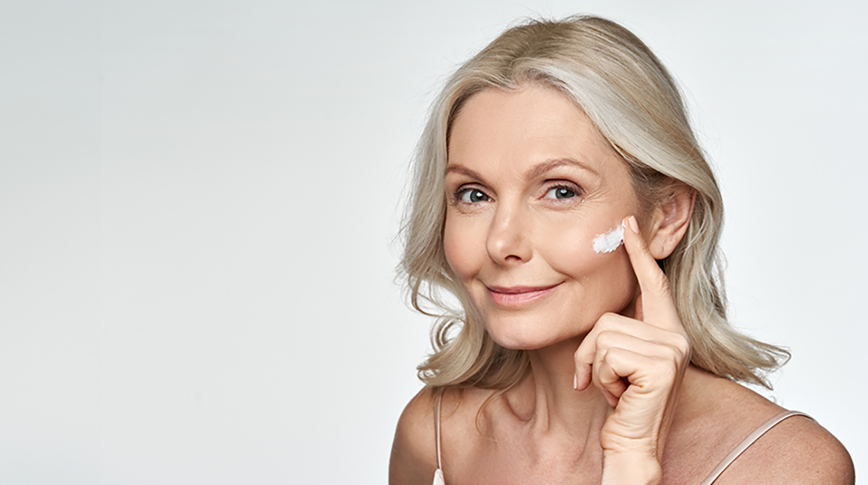 Model, das sich Gesichtscreme auf die Wangen aufträgt