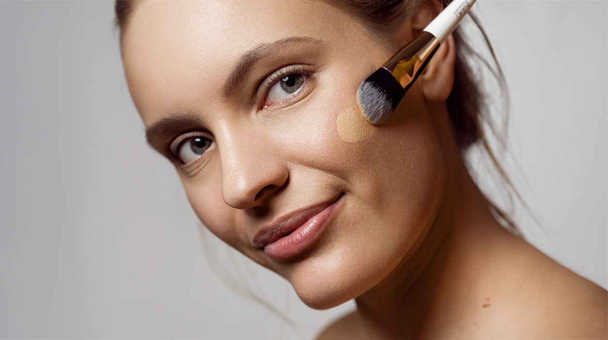 Frau, die sich Foundation mit einem Pinsel aufträgt